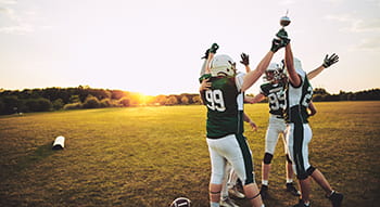 team members cheer and hold a trophy in a field