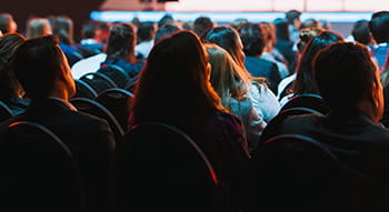 a crowd of attendees watch a conference